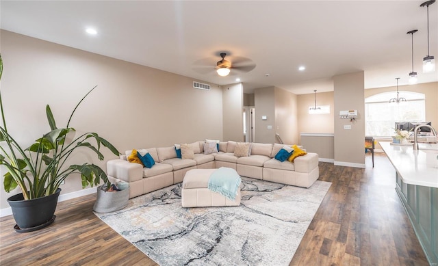 living area with visible vents, dark wood finished floors, baseboards, and ceiling fan