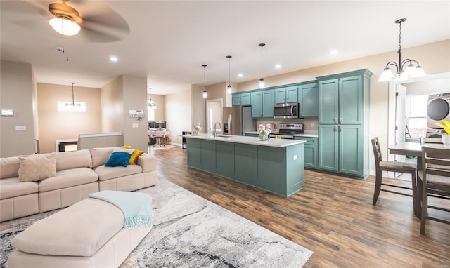 kitchen with pendant lighting, stainless steel appliances, light countertops, open floor plan, and an island with sink