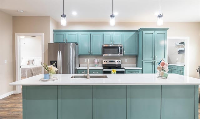 kitchen featuring a kitchen island with sink, stainless steel appliances, light countertops, and decorative light fixtures