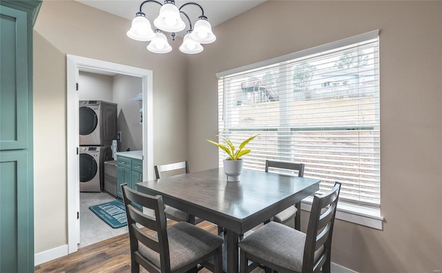 dining room featuring stacked washer and dryer, light wood-style floors, and an inviting chandelier