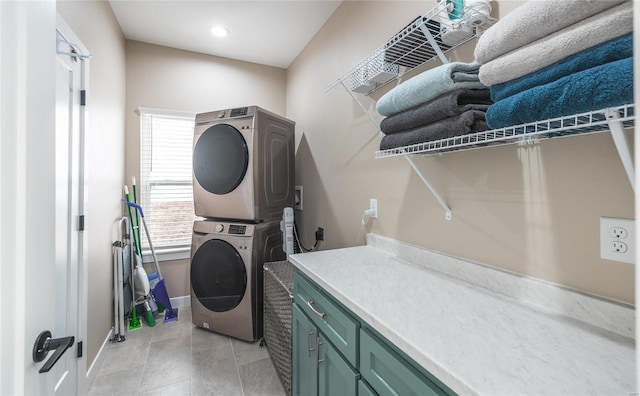 washroom featuring stacked washer and dryer, cabinet space, baseboards, and light tile patterned floors