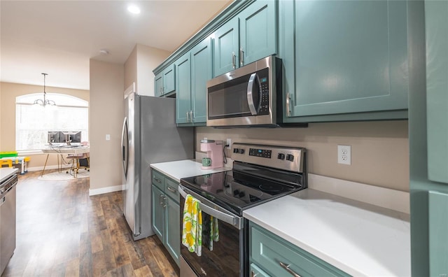 kitchen with baseboards, dark wood-style floors, appliances with stainless steel finishes, hanging light fixtures, and light countertops