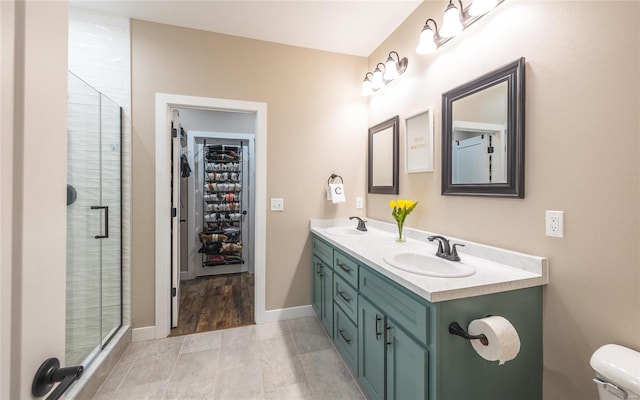 full bath featuring a spacious closet, double vanity, a stall shower, and a sink