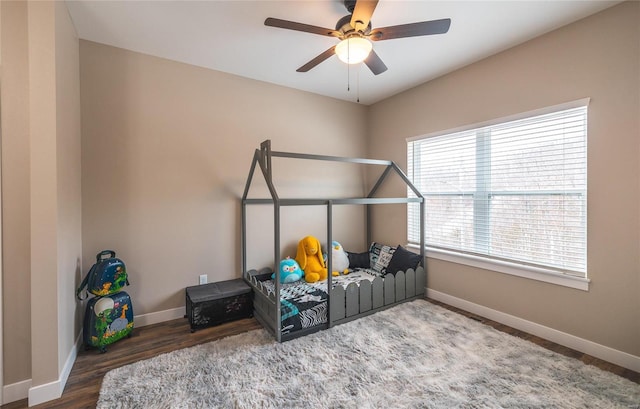 bedroom with ceiling fan, baseboards, and wood finished floors