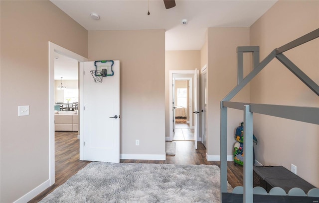 interior space with wood finished floors, a ceiling fan, and baseboards