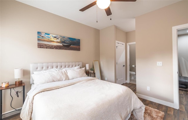 bedroom featuring dark wood finished floors, ensuite bathroom, a baseboard heating unit, ceiling fan, and baseboards