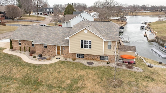 exterior space featuring brick siding, roof with shingles, and a front yard