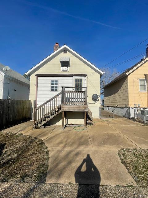 rear view of property with a chimney and fence