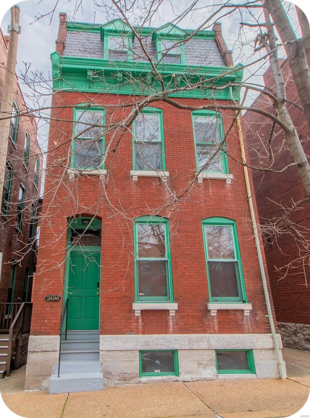 victorian home featuring entry steps, brick siding, and mansard roof