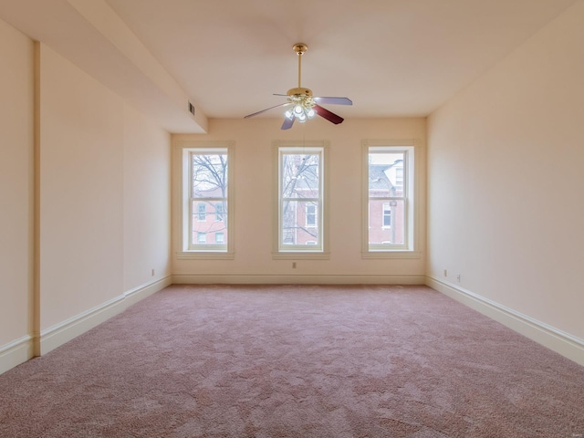 empty room featuring light carpet, ceiling fan, visible vents, and baseboards