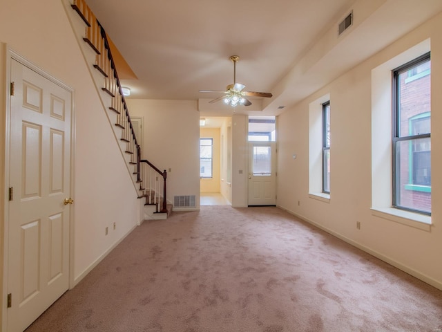 entrance foyer with light carpet, stairway, baseboards, and visible vents