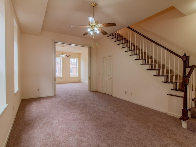 unfurnished living room with carpet, ceiling fan, stairway, and baseboards