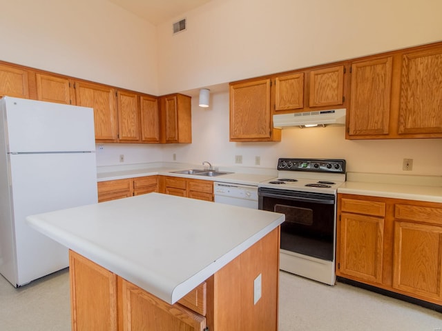 kitchen with under cabinet range hood, white appliances, a sink, light countertops, and a center island