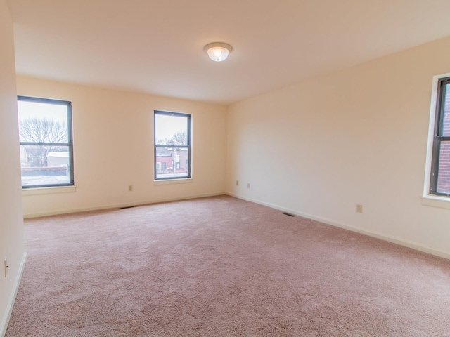 spare room with light carpet, baseboards, and a wealth of natural light