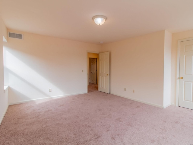 spare room with light carpet, visible vents, and baseboards