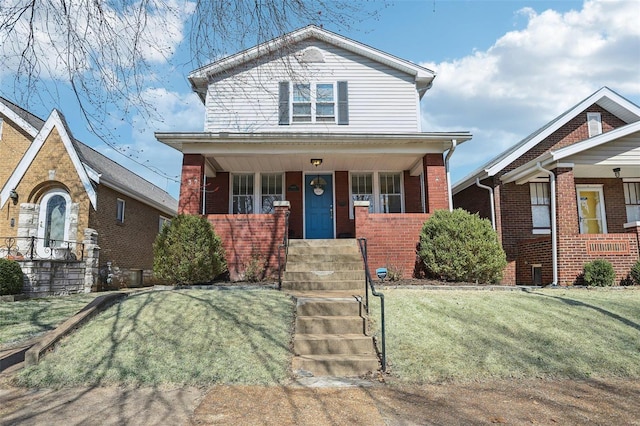 view of front of property with a porch, brick siding, and a front lawn