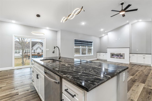 kitchen with sink, dark stone countertops, dishwasher, pendant lighting, and white cabinets