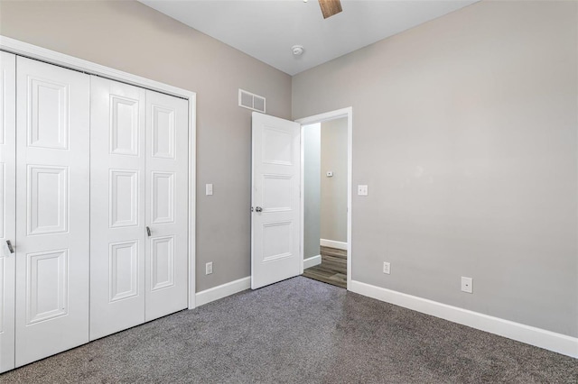 unfurnished bedroom featuring ceiling fan, dark carpet, and a closet