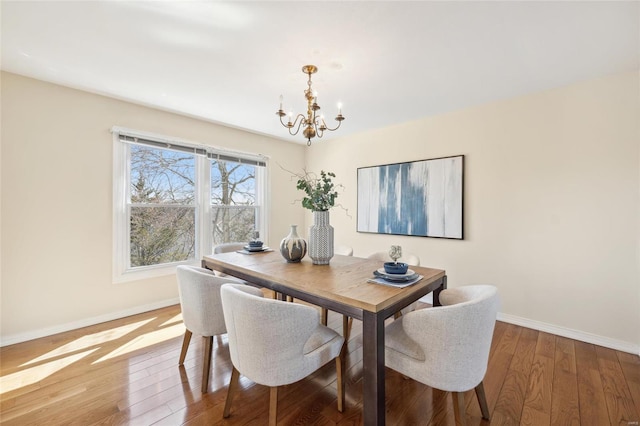 dining area with a notable chandelier, baseboards, and hardwood / wood-style flooring