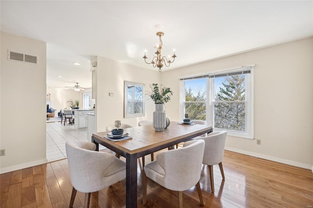 dining room with baseboards, visible vents, light wood finished floors, and a chandelier