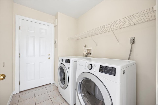 laundry area with light tile patterned flooring, laundry area, washing machine and dryer, and baseboards