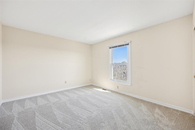 spare room featuring baseboards and light carpet