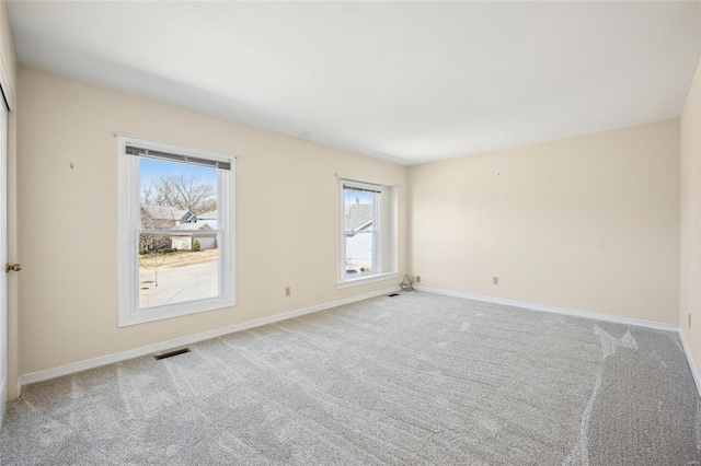 empty room with visible vents, baseboards, and carpet