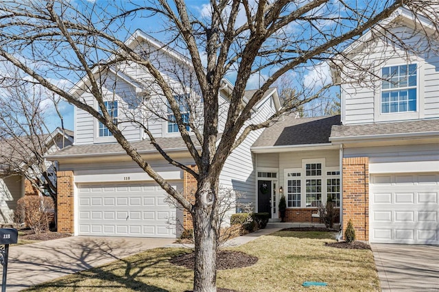 traditional home with brick siding, a shingled roof, an attached garage, a front yard, and driveway