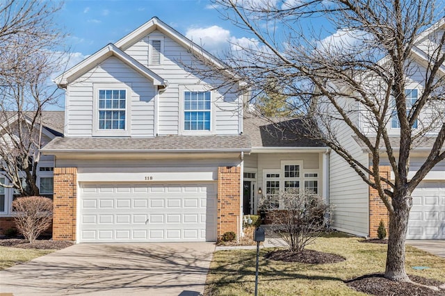 traditional-style home with driveway, roof with shingles, an attached garage, and brick siding