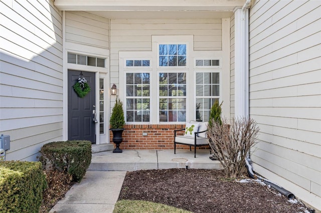 entrance to property with a porch and brick siding