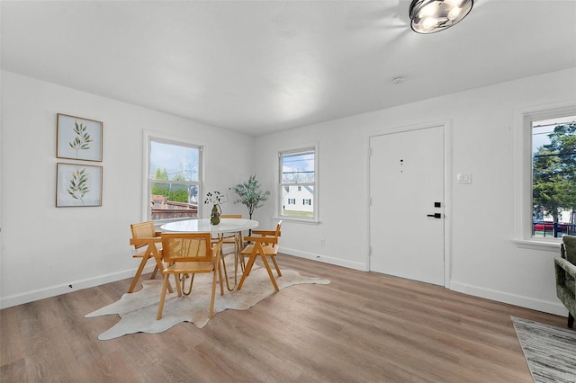 dining space with a wealth of natural light, baseboards, and light wood-style flooring