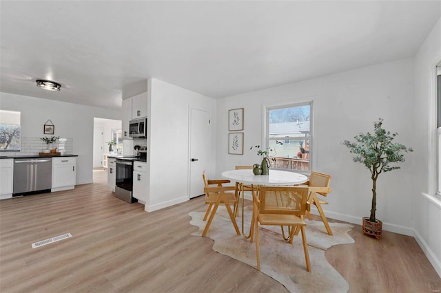 dining space with visible vents, baseboards, and light wood-style flooring