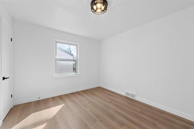 spare room with visible vents, baseboards, and wood finished floors