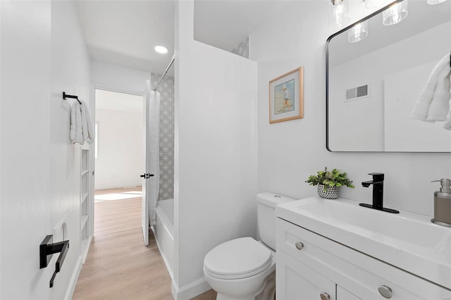 bathroom with visible vents, toilet, shower / tub combo, wood finished floors, and vanity