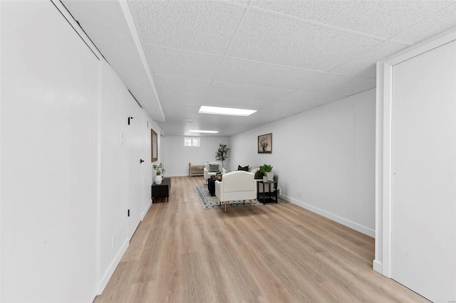 living room with baseboards, a paneled ceiling, and light wood-style floors