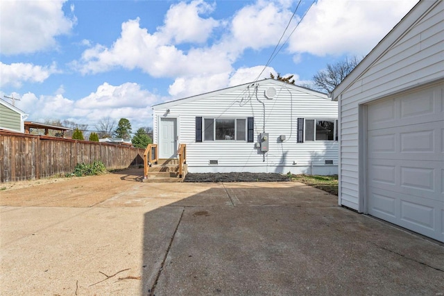 rear view of house with crawl space, entry steps, a garage, and fence