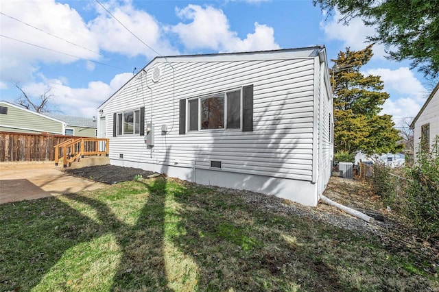 view of property exterior with crawl space, a yard, and fence