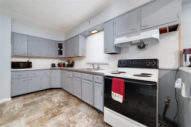 kitchen with a textured ceiling, black microwave, under cabinet range hood, light countertops, and electric range oven