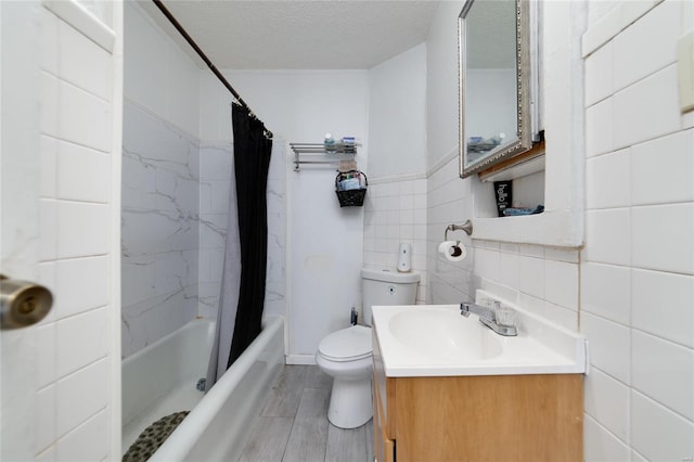 bathroom with a textured ceiling, toilet, vanity, tile walls, and shower / bath combination with curtain
