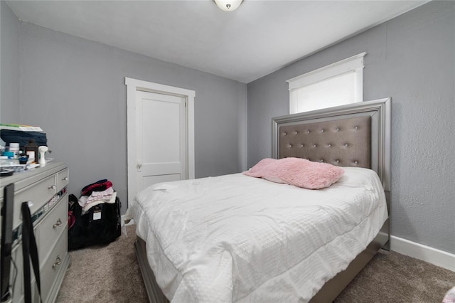 bedroom with dark colored carpet and baseboards