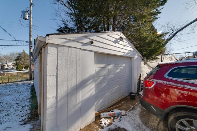 snow covered garage with a garage and fence