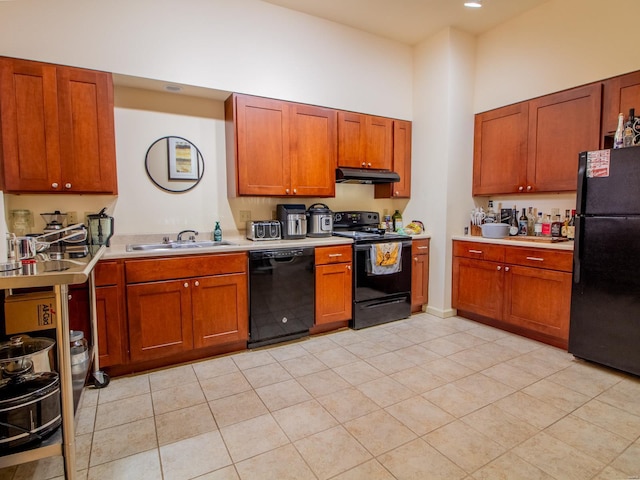 kitchen featuring a towering ceiling, under cabinet range hood, light countertops, black appliances, and a sink