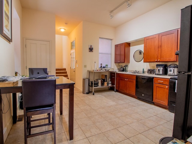 kitchen with light countertops, brown cabinets, black dishwasher, and light tile patterned flooring