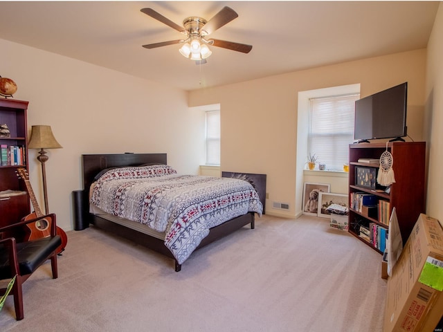 bedroom with light carpet, ceiling fan, multiple windows, and visible vents