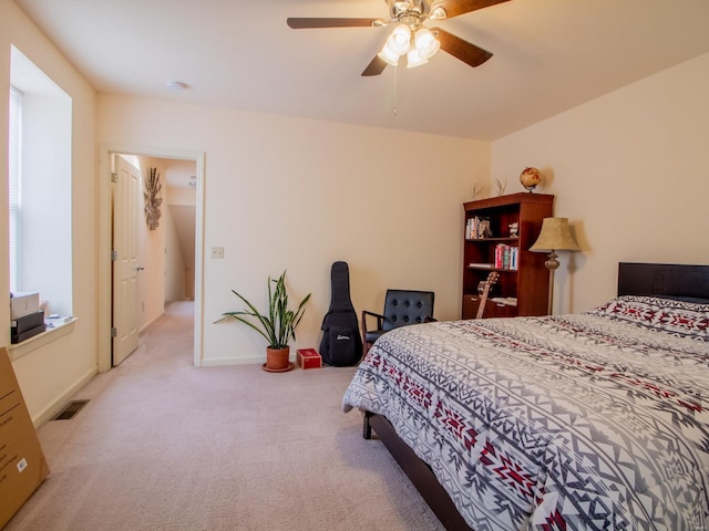 bedroom with baseboards, visible vents, light colored carpet, and a ceiling fan