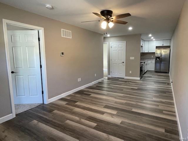 unfurnished living room featuring ceiling fan and dark wood-type flooring