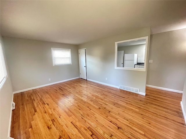 unfurnished room featuring baseboards, visible vents, and wood finished floors