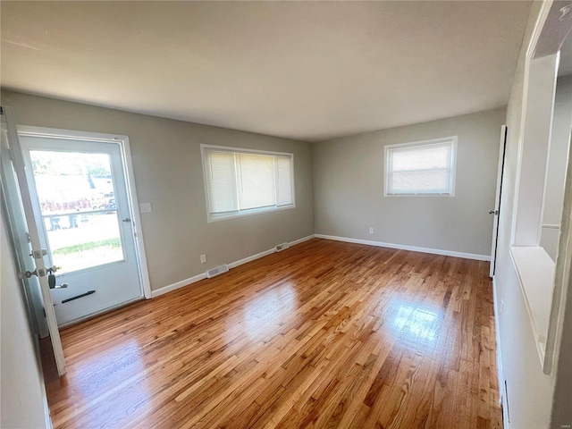 unfurnished room with light wood-style flooring, visible vents, and baseboards