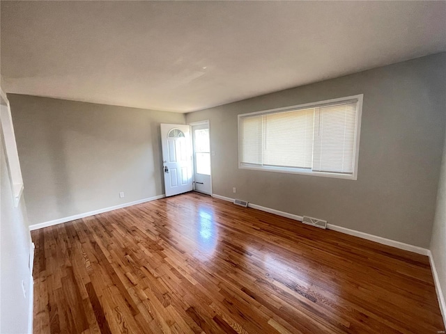 spare room with visible vents, baseboards, and wood finished floors