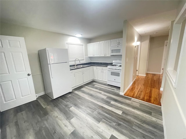 kitchen with dark wood-style floors, white appliances, dark countertops, and a sink